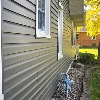 New vinyl siding installation — olive grey lap siding with white trim on residential home exterior