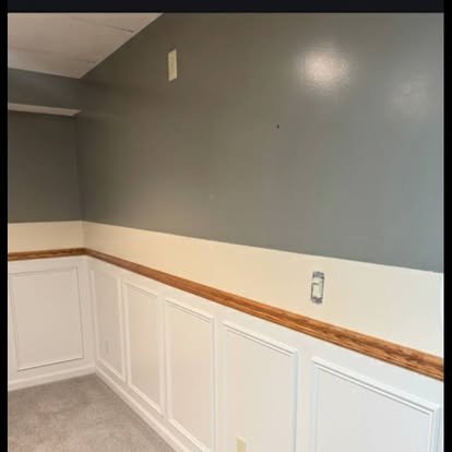 Interior wainscoting installation — white board and batten paneling with stained oak cap rail
