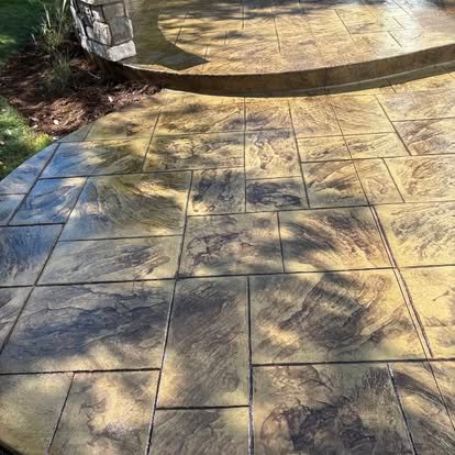 Stamped concrete patio close-up — rich amber stone tile pattern with decorative curved border
