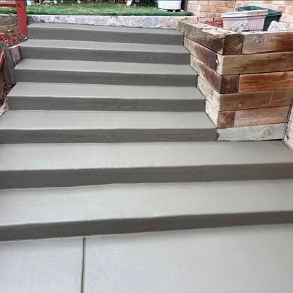 Poured concrete steps — clean broom finish with precision-formed risers alongside timber retaining wall