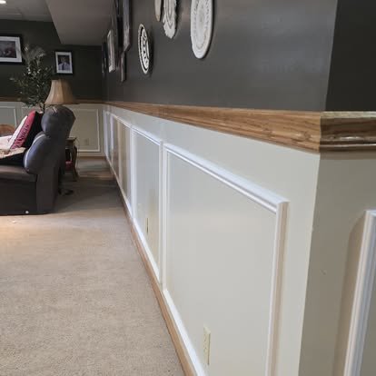 Interior wainscoting — white raised panel with natural oak cap rail along full accent wall